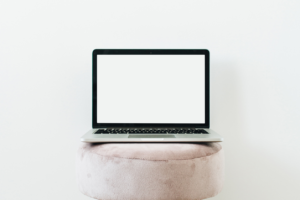 Blank laptop sits on round white cushion against a white background -  - Above The Bar -  - Above The Bar